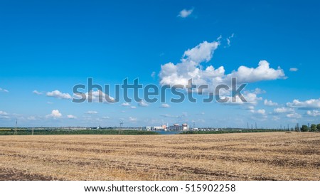 South Ukrainian Nuclear Power Plant and Wheat field against the blue sky with white clouds