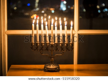 Low key image of with menorah (candlestick with 8 candles) by the window with the night view on Tel Aviv, Israel. Candles burning on the Jewish holiday Hanukkah menorah stock image.