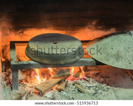 Picture of the stone bread oven stove with burning wood fire and red flames inside. Image of the burning wood fire against the background of the sooty wall.