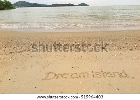 written words "Dream Island" on sand of beach
