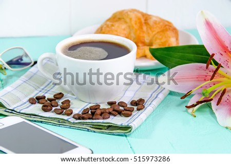 A cup of coffee with croissant on blue table background in the morning . take a break with  fresh flower from garden - idea concept.