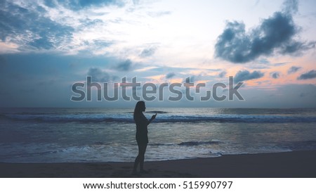 Silhouettes of a woman using telephone on the beach during sunset 
