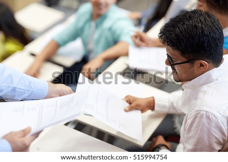 education, high school, university, learning and people concept - teacher giving exam test to indian student man at lecture Royalty-Free Stock Photo #515994754