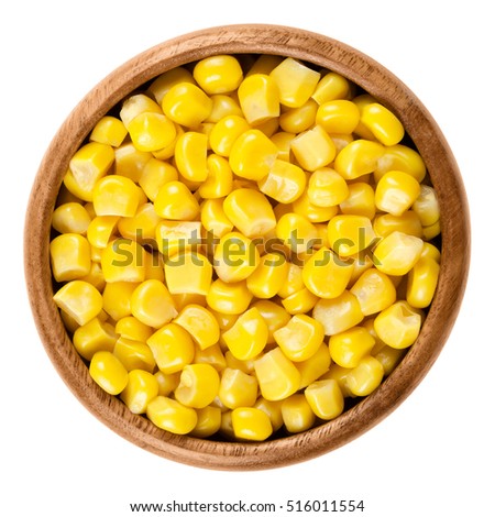 Sweet corn kernels in wooden bowl over white. Cooked canned yellow vegetable maize, Zea mays, also called sugar or pole corn, a vegetarian staple food. Isolated macro food photo close up from above. Royalty-Free Stock Photo #516011554
