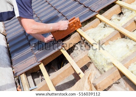 a roofer laying tile on the roof Royalty-Free Stock Photo #516039112