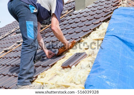 a roofer laying tile on the roof Royalty-Free Stock Photo #516039328