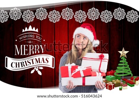 Thoughtful woman in santa hat holding christmas gifts against digitally generated background