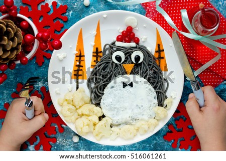 Fun food art idea for kids - penguin black spagehetti with fried egg and vegetables for Christmas or New Year festive dinner