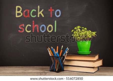 Back to school concept - books on the desk over the blackboard