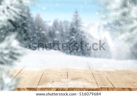 wooden desk of free space and winter background of snow and mountains 