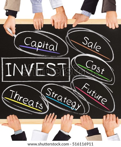 Photo of business hands holding blackboard and writing INVEST concept