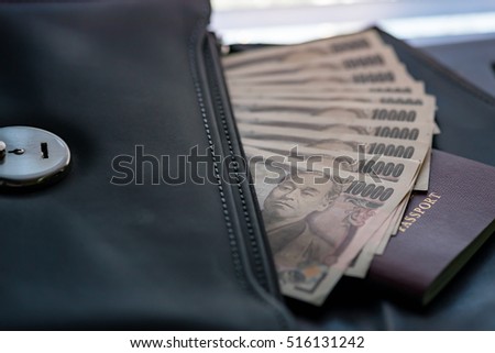 Close up of ten thousand yen banknote call ichiman  banknote in japan inside black business leather bag for traveler.