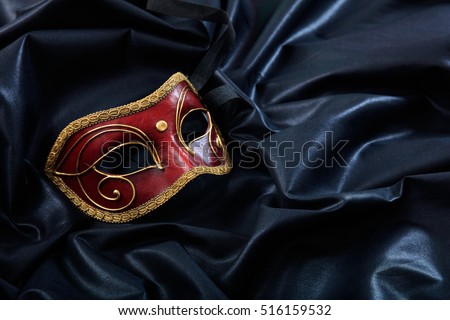 Red handmade carnival mask on black satin background, copy space