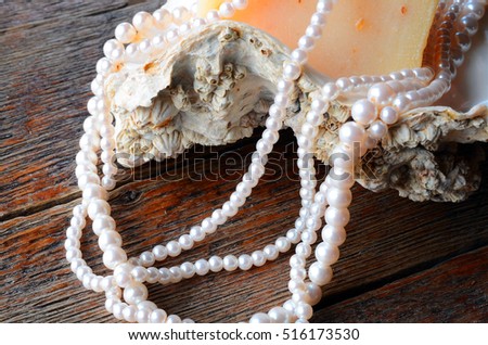 A close up image of a string of pearls on an oyster shell with a bar of homemade oatmeal soap. 