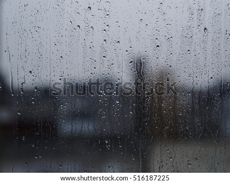Rain drops on window glass buildings in background