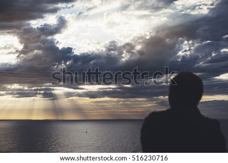 Clouds blue sky and sunlight sunset on horizon ocean Northern Spain Basque Country. Outline looking blurred travel hipster on background seascape dramatic rays sunrise. Relax view sea, mockup nature 
