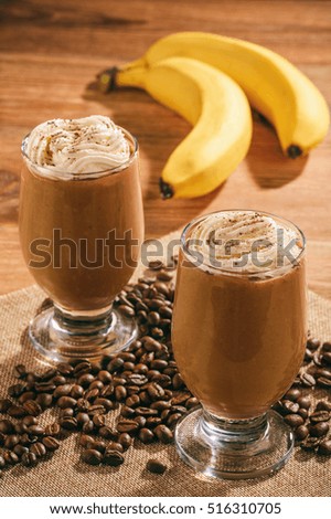 Coffee milk cocktailsl with banana on wooden background.