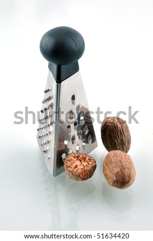 Small grater for spices and three nutmeg photographed on a white background with reflection