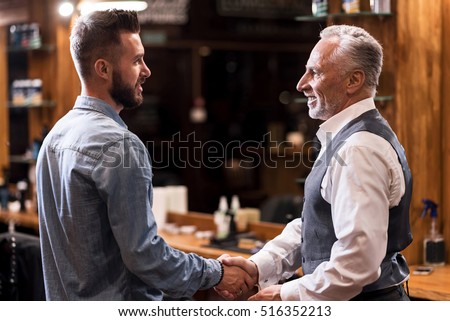 Barber and client shaking hands Royalty-Free Stock Photo #516352213