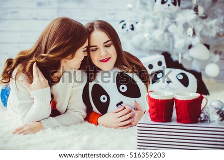 Two happy and beautiful sisters lying near Christmas tree