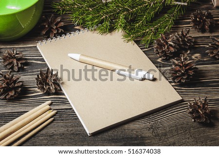 view of notebook in the center of cute Christmas decoration, cones, fir tree branch