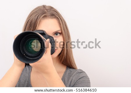 Beautiful young woman with camera. Full isolated woman with dslr. Woman holding a camera - isolated over a white background. Professional female photographer taking snapshot.Photographer Shooting You