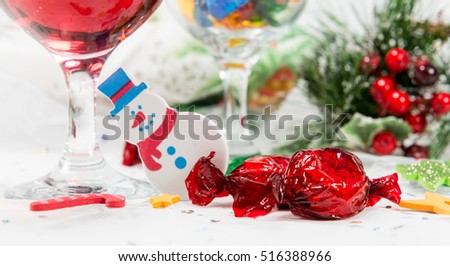 Close up of festive Christmas table with snowman decoration, wine and red chocolate candy twist wrapped sweets. Celebrating a happy Christmas.