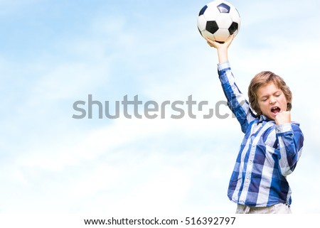 Child with soccer ball against blue sky with clouds
