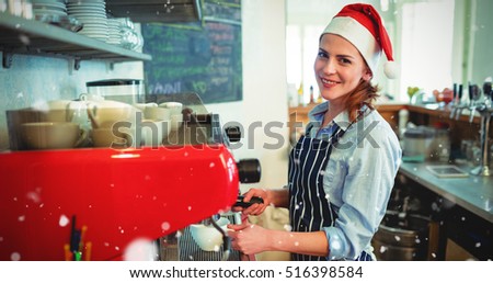 Portrait of happy waitress wearing Santa hat against snow falling