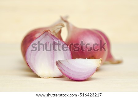 Shallots, onions, isolated on wood background