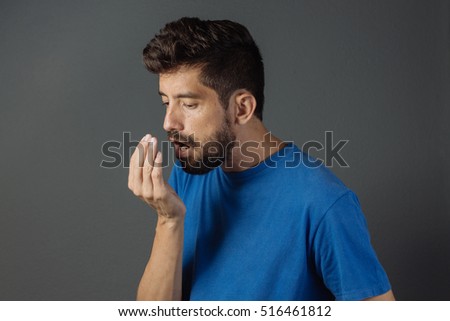 Bad breath. Halitosis concept. Young man checking his breath with his hand. Royalty-Free Stock Photo #516461812