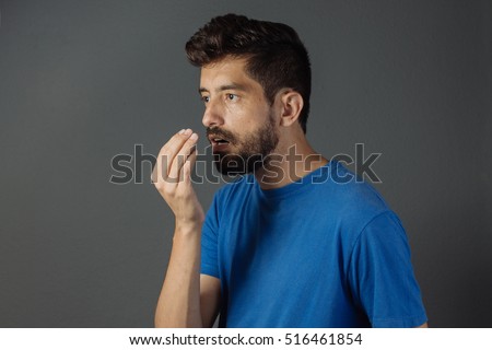Bad breath. Halitosis concept. Young man checking his breath with his hand. Royalty-Free Stock Photo #516461854