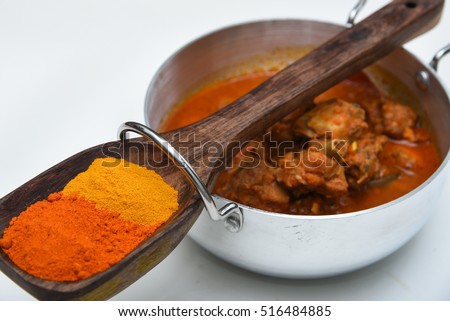 Hot and spicy chicken/mutton/lamb/meat curry and a wooden spoon/untensil, Kerala, India. Food prepared using Indian spices turmeric, coriander, chilli, garam masala powder.