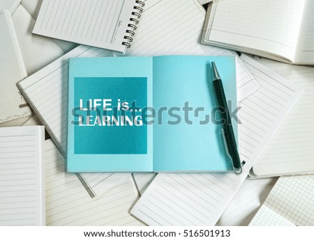 Manny empty notebook paper and note pad background with one blue book and life is learning quotes