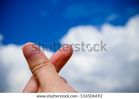 Finger heart sign, mini heart against blue sky