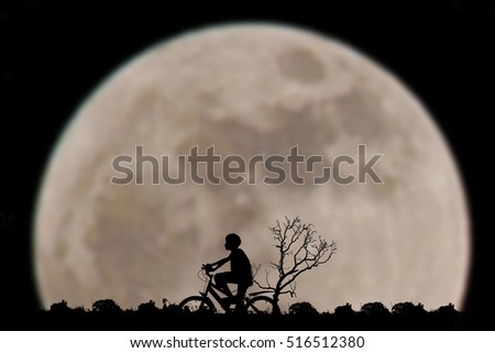 Silhouette of boy ride bike on full moon background