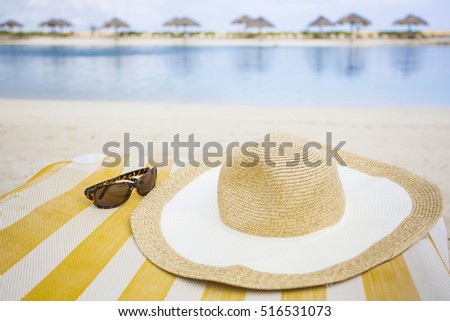 Sun hat and sunglasses on a lounge chair at the beach