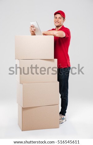 Smiling delivery man behind the boxes. isolated gray background