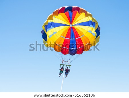 Happy couple Parasailing in Dominicana beach in summer. Couple under parachute hanging mid air. Having fun. Tropical Paradise. Positive human emotions, feelings, family, children, travel, vacation. Royalty-Free Stock Photo #516562186