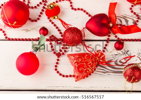 Beautiful red decorations for the Christmas tree. Detail of Christmas balls and decorations. Red balls and beads on a wooden background.