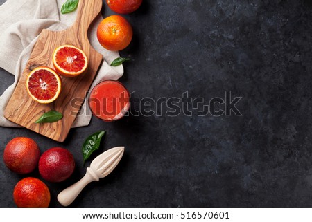 Fresh citruses and red orange juice on dark stone background. Top view with copy space