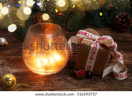 Christmas magic glowing light with handmade gift box and evergreen twig on wooden background with bokeh lights