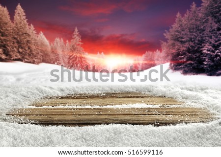 Wooden desk of free space for your decoration with cold white snow and landscape of winter mountains with sunset at golden hour. 