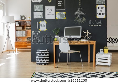 Creative working space with computer desk and accessories in flat with blackboard wall Royalty-Free Stock Photo #516611200