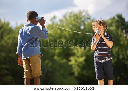 Two boys play tin can telephone in the summer Royalty-Free Stock Photo #516611551