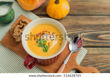 A bowl of homemade creamy pumpkin soup on wooden background.