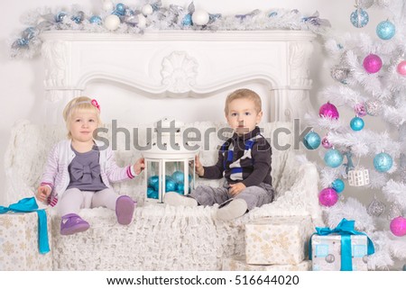 Little boy and girl sitting on the background of the Christmas t