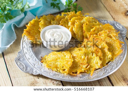Homemade traditional potato pancakes, served with sour cream sauce. Hanukkah holiday meal on vintage wooden background. 