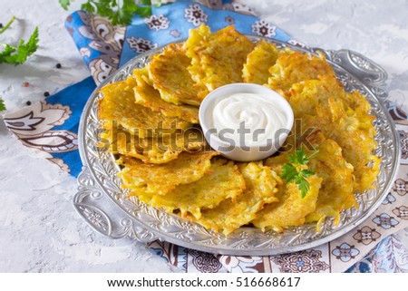 Homemade traditional potato pancakes, served with sour cream sauce, top view. Hanukkah holiday meal on vintage concrete background.