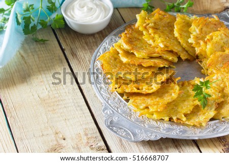 Homemade traditional potato pancakes, served with sour cream sauce. Hanukkah holiday meal on vintage wooden background. Copy space.